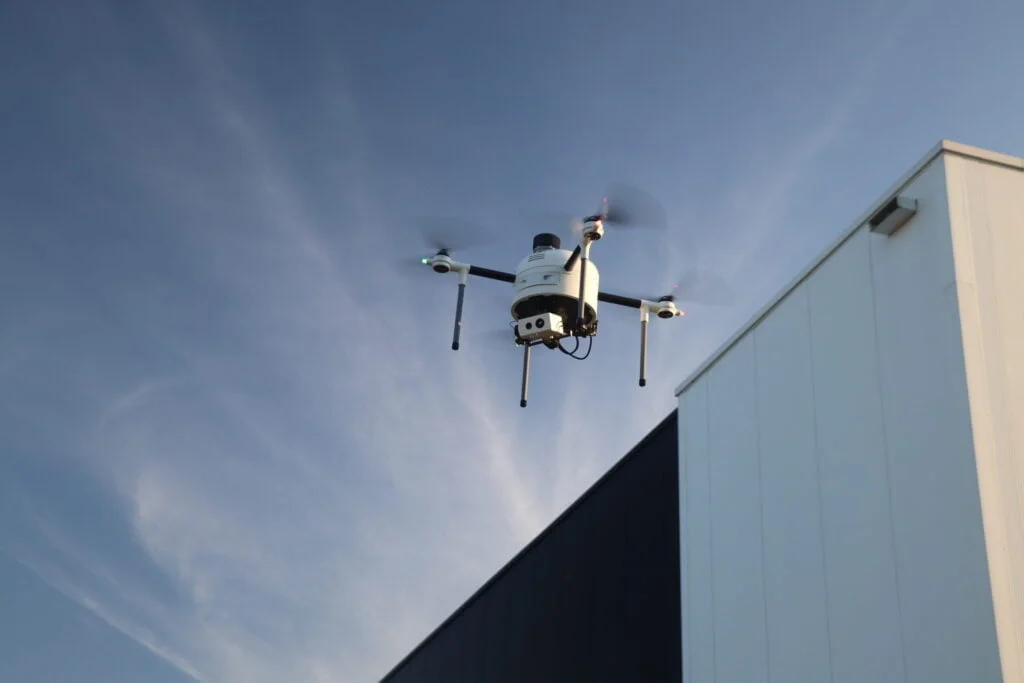 Drone in vlucht bij industrieel gebouw, demonstratie van 3D geprinte onderdelen in gebruik